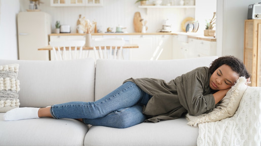Foto: Eine Frau liegt auf einer Couch und schläft.