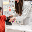 Foto: Eine Person in weißem Kittel legt in der Apotheke einer weiteren Person eine Oberarmmanschette an
