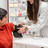 Foto: Eine Person in weißem Kittel legt in der Apotheke einer weiteren Person eine Oberarmmanschette an