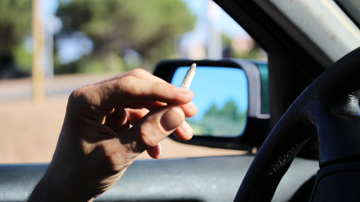 Foto: Eine Hand, die einen Joint hält im Auto.