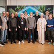 Four 20 Pharma setzt neue Impulse für die Cannabis-Medizin Elf Personen posieren bei einer Veranstaltung vor einer dekorativen Hintergrundwand mit Pflanzenmotiv in einem modernen Innenraum. Quelle: Be.A.Star-Productions