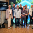 „Gruppenfoto von neun Personen auf einer Konferenz, stehend vor einer beleuchteten Wand; links im Bild steht ein Bildschirm mit der Aufschrift ‚Circle of Experts‘.“