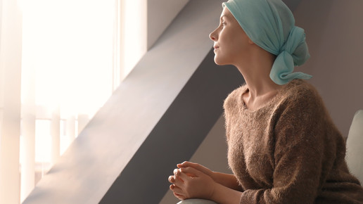 Foto: Eine Frau mit Kopftusch sieht aus dem Fenster.