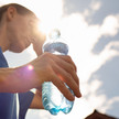 Foto: Eine Frau mit Wasserflasche in der Hand wischt sich den Schweiß von der Stirn.
