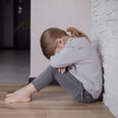 Foto: Ein Kind sitzt auf dem Boden und vergräbt sein Gesicht