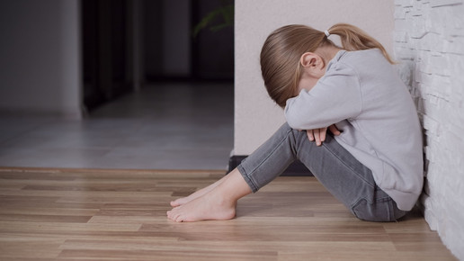Foto: Ein Kind sitzt auf dem Boden und vergräbt sein Gesicht