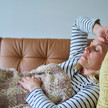 Symbolbild, Frau liegt krank auf der Couch