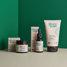 Drei green team Pflegeprodukte vor grünem und beigem Hintergrund: eine Feuchtigkeitscreme, ein Intensivserum und ein Reinigungsgel mit Verpackungen in Beige und Grün. Die Tuben und Fläschchen tragen das grüne green team Logo.