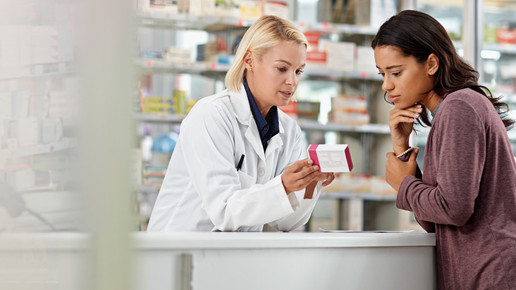 Foto: Eine Person im Kittel in der Apotheke berät eine Person im Handverkauf.