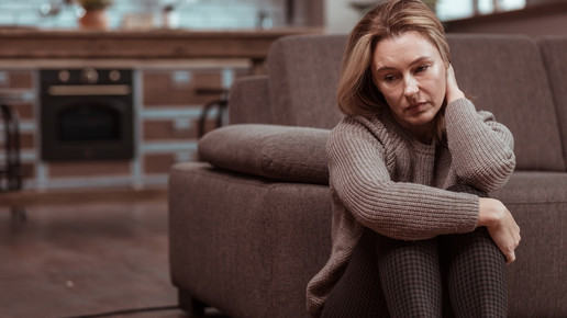 Symbolbild Einsamkeit, Frau sitzt traurig allein zu Hause