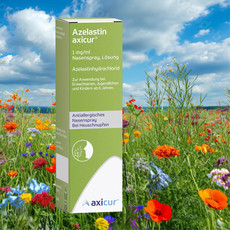 Verpackung des Nasensprays Azelastin axicur (1 mg/ml) steht aufrecht in einer bunten Blumenwiese unter blauem Himmel mit Wolken. Auf der grünen Packung sind Angaben zu Wirkstoff (Azelastinhydrochlorid) und Anwendung bei Heuschnupfen für Erwachsene, Jugendliche und Kinder ab 6 Jahren zu sehen.