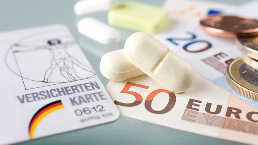 Foto: Tabletten, Geldscheine und Münzen neben einer Versichertenkarte auf einer Oberfläche.