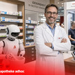 Team ersetzt: Roboter übernehmen Pilot-Apotheke Lächelnder Apotheker in seiner Apotheke umgeben von Robotern statt Angestellten