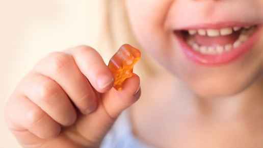 Ein Kind hält ein Gummibärchen in der Hand.