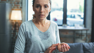 Foto: Eine weibliche Person mit sichtbaren Schweißflecken auf der Kleidung