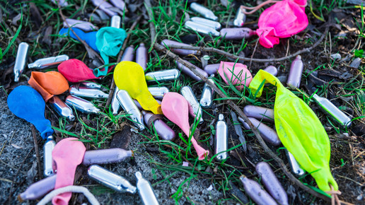 Foto: Luftballons und Lachgas-Kartuschen auf einer Wiese