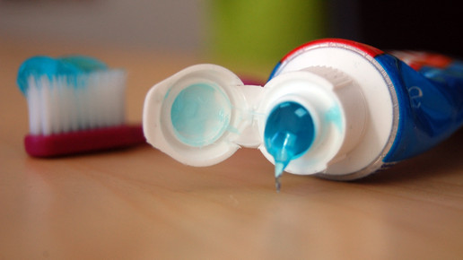 offene Zahnpastatube mit Zahnbürste im Hintergrund