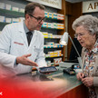 Zero Pay Day: Apotheke drosselt Leistungen KI-Bild zeigt Apotheker, der Rentnerin eine Tablette überreicht