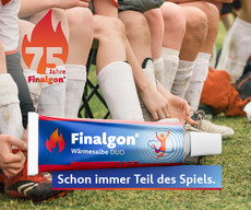 Fussballmanschaft sitzt auf einer Bank auf dem Rasen. Nur die Stollen sind sichtbar und ein übergroßes Packshot der Finalgon Tube und das 75 Jahre Jubiläumslogo. Finalgon- Schon immer Teil des Spiels