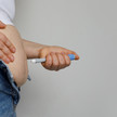 Foto: Eine übergewichtige Person setzt einen GLP-1-Pen am Bauch an.