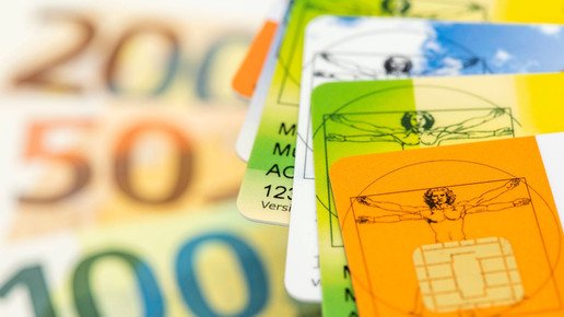 Gesundheitskarten liegt über Geldscheinen als Symbolbild für steigende Kosten im Gesundheitswesen