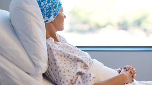 Foto: Eine Frau mit Kopftuch im Krankenbett schaut aus dem Fenster