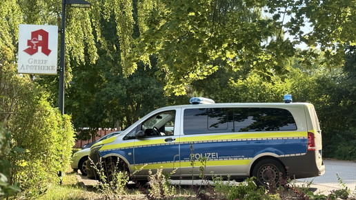 Ein Apotheken-A-Schild mit einem Polizeiwagen.