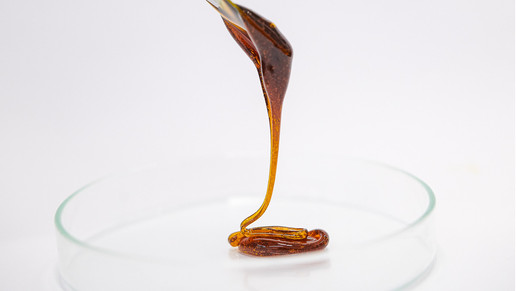 Cannabis Rohextrakt tropft auf eine Glasschale von einem Löffel