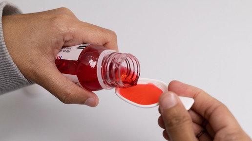 Foto: Eine Person dosiert Hustensaft auf einen Messlöffel.