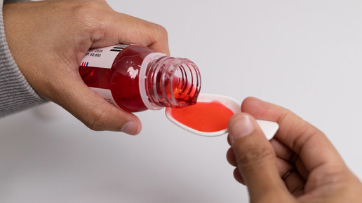 Foto: Eine Person dosiert Hustensaft auf einen Messlöffel.