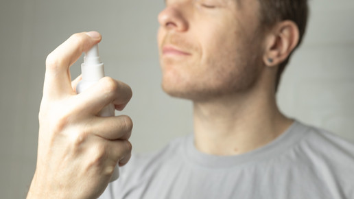 Foto: Eine Person hält eine Flasche in der Hand und sprüht sich etwas ins Gesicht
