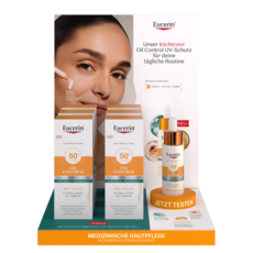 Frontansicht eines Displays mit einer Frau, die Serum aufträgt. Text: „Unser leichtester Oil Control UV-Schutz“. Davor stehen Produktpackungen und ein Tester-Flakon auf einem orangen Sockel mit „JETZT TESTEN“.