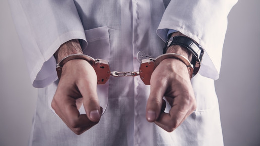 Foto: Eine Person im Kittel mit Handschellen