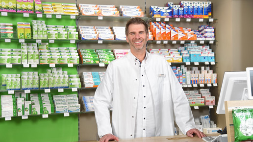 Dr. Alexander Schröder, Apotheker steht mit weißem Apothekerkittel in seiner Offizin.
