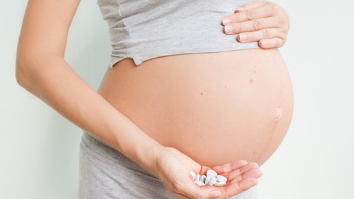 Symbolbild, schwangere Frau mit Tabletten in der Hand