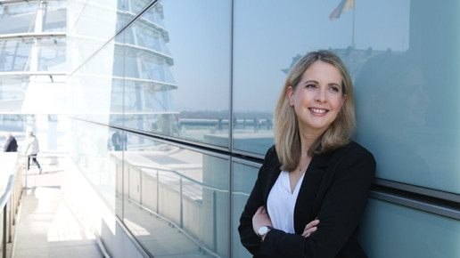 Verena Hubertz in der Außenkulisse des Bundestages an eine Wand gelehnt