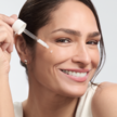 Nahaufnahme einer Frau mit Pipette und Serumtröpfchen auf der Wange. Sie lächelt und vermittelt das Gefühl gepflegter, glatter Haut – passend zur Anti-Aging-Wirkung des Eucerin Serums.