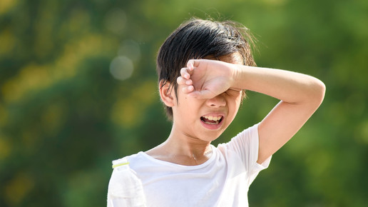 Foto: Ein Junge schwitzt draußen in der Sonne.
