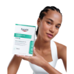 Eine junge Frau hält lächelnd eine Packung Eucerin Dermopure Clinical in die Kamera.