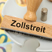 China: Gegensanktionen auf EU-Medizinprodukte Symbolbild für Zollstreit – Gerdscheine und Stempel, auf dem "Zollstreit" steht
